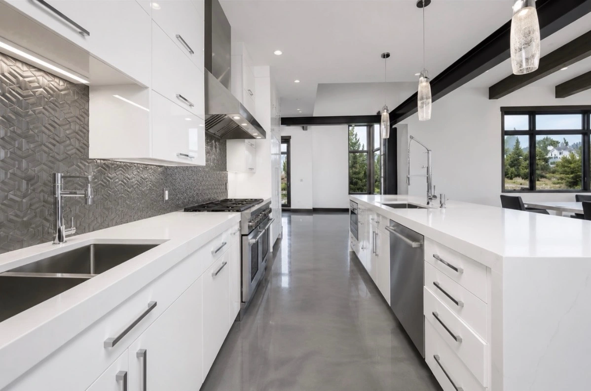 Additional view of quartz kitchen countertops throughout with 2½-inch mitered edges, a waterfall island, two sinks, white cabinetry and dark ceiling beams