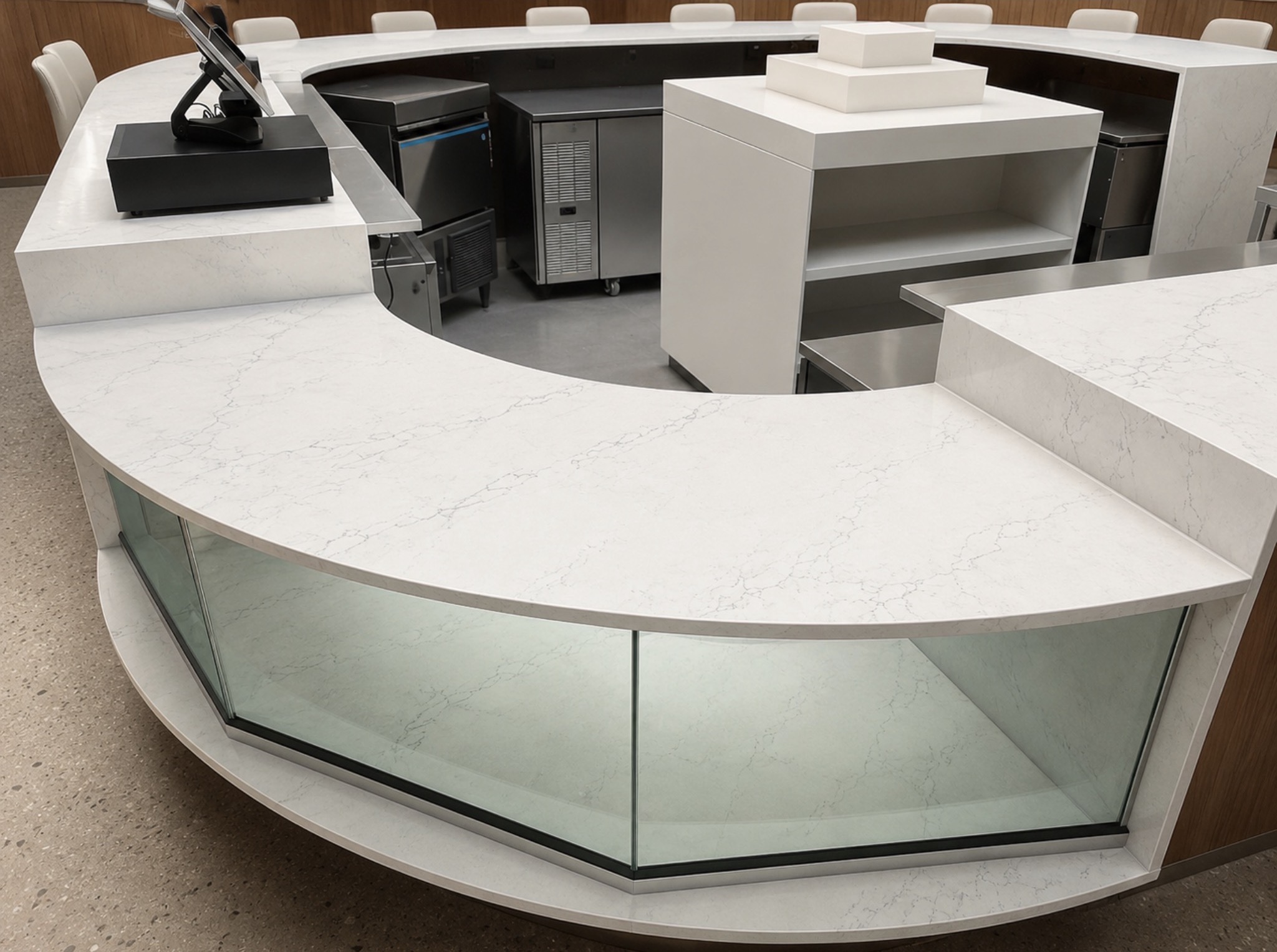Close-up of project 21 showing curved white countertops with fine gray veining, raised sections and a glass-front display