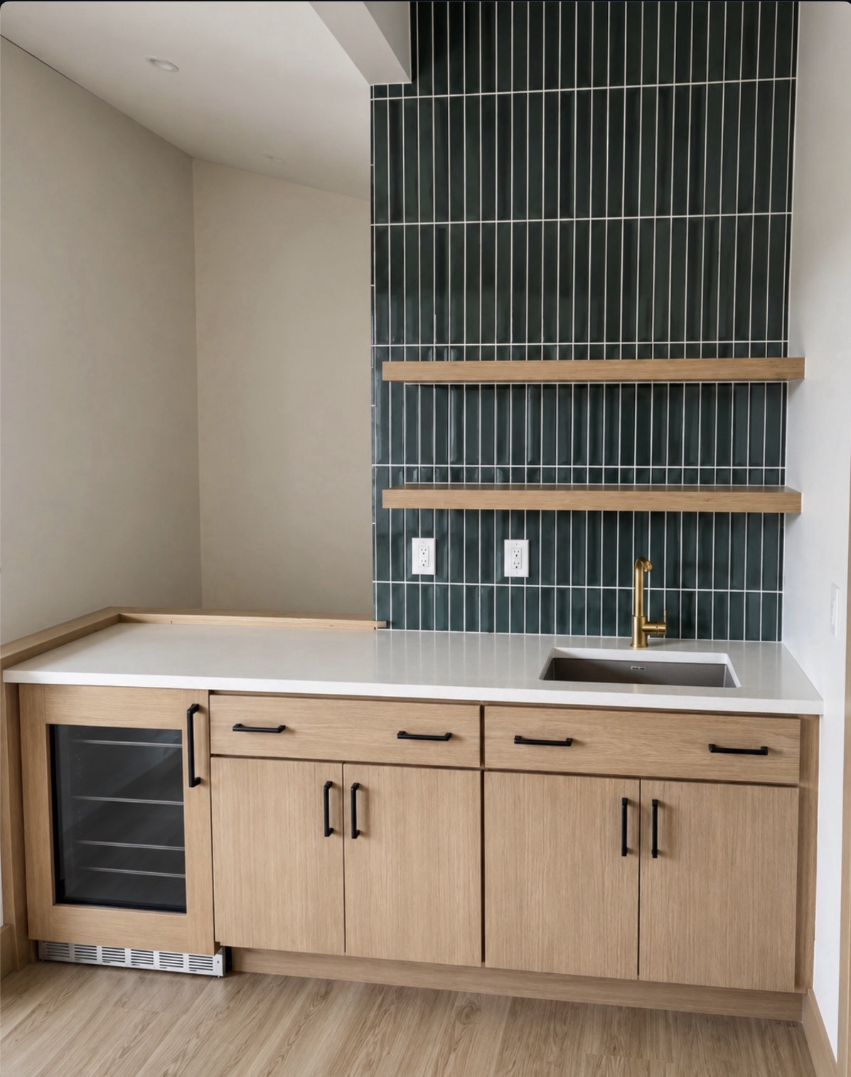 Quartz wet bar countertop with a 3 cm square eased edge, undermount sink, brass faucet, wood cabinets and dark green tile backsplash