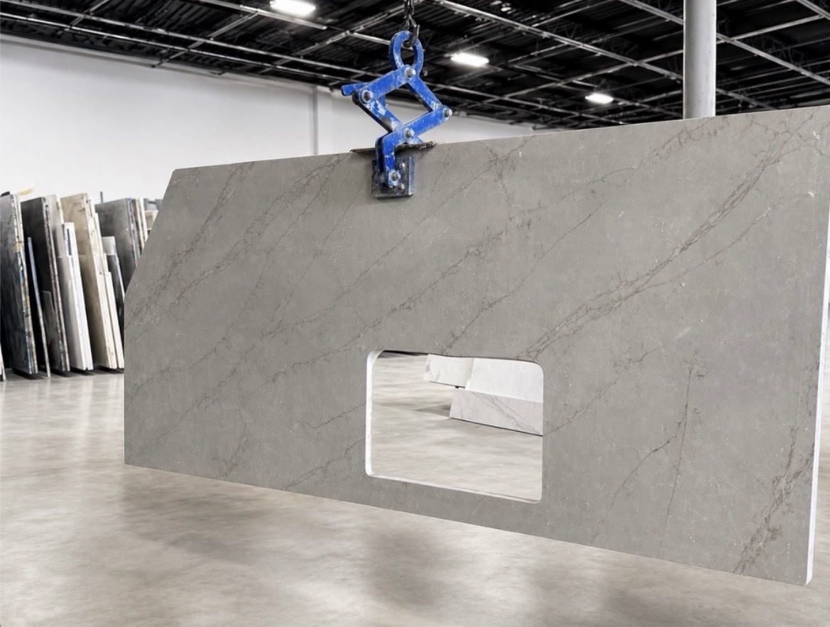Light gray veined countertop with a rectangular sink cutout held by a lifting clamp in the shop